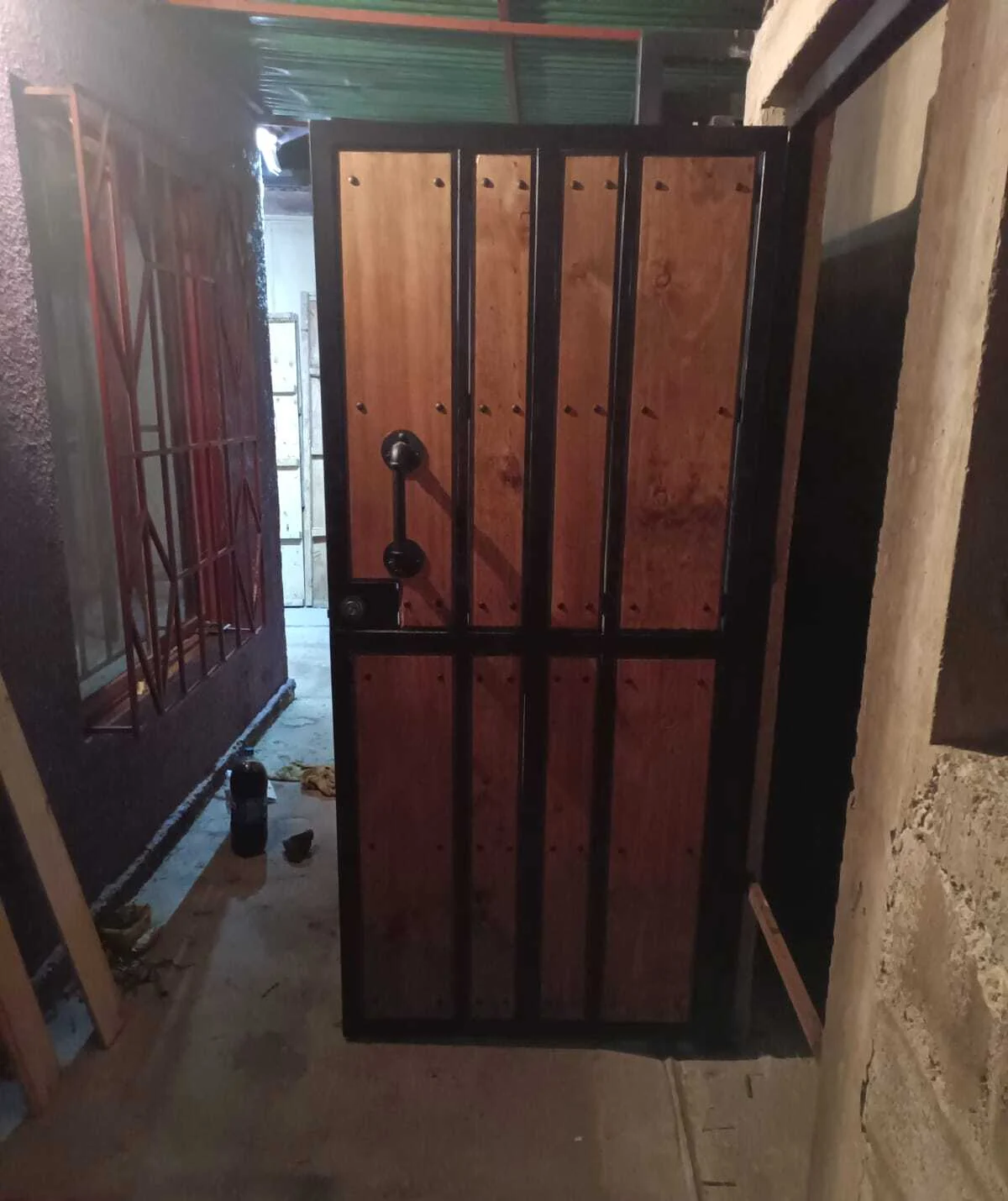 Puerta peatonal con estructura metálica y paneles de madera